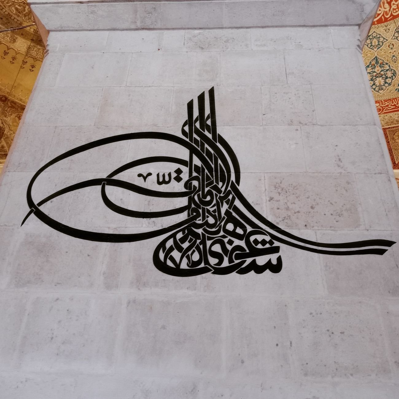 Elegant Arabic calligraphy artwork on a stone wall, showcasing Islamic art.